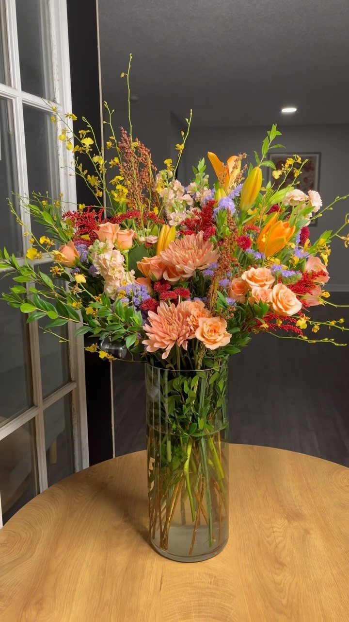 Colorful floral arrangement in a glass vase sitting on a wooden table.