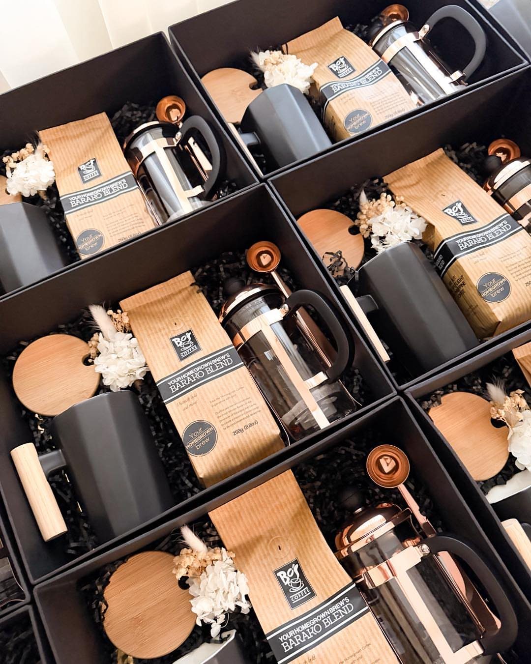 Coffee gift sets in black boxes with French presses, coffee bags, and mugs.