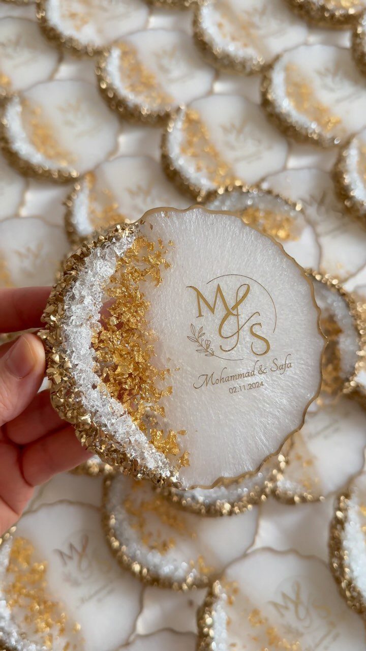 Personalized white resin coasters with gold foil edges and gold monogram lettering.