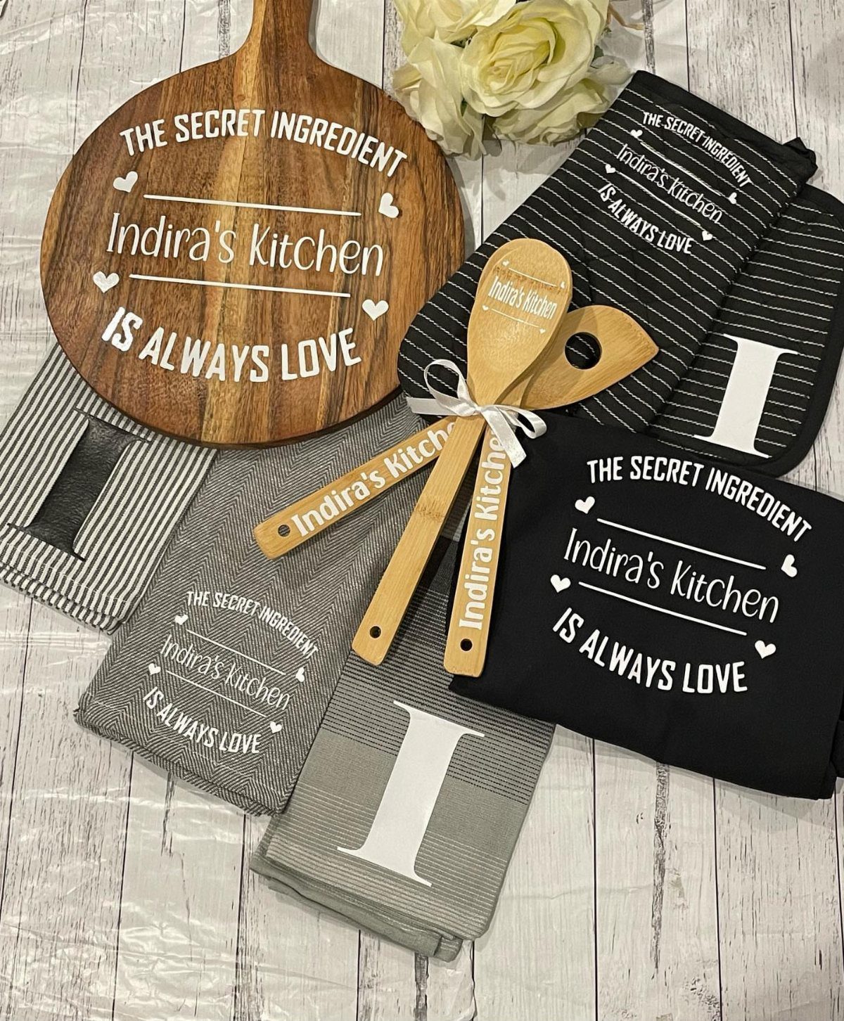 Personalized kitchen gift set with wooden cutting board, towels, and spoons for Indira's Kitchen.