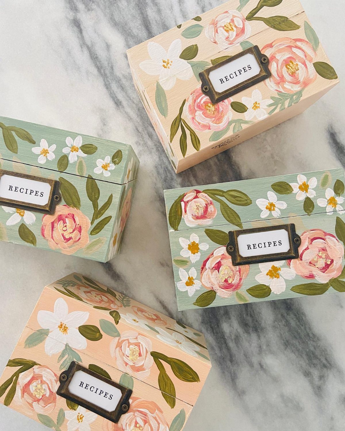 Floral recipe boxes with labels resting on a white marble countertop.